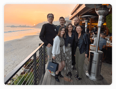 Men and women posing on a beachside patio